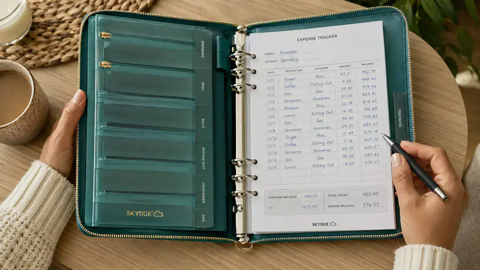 Budget binder open to expense tracking sheets with handwritten monthly totals and remaining balances in each category
